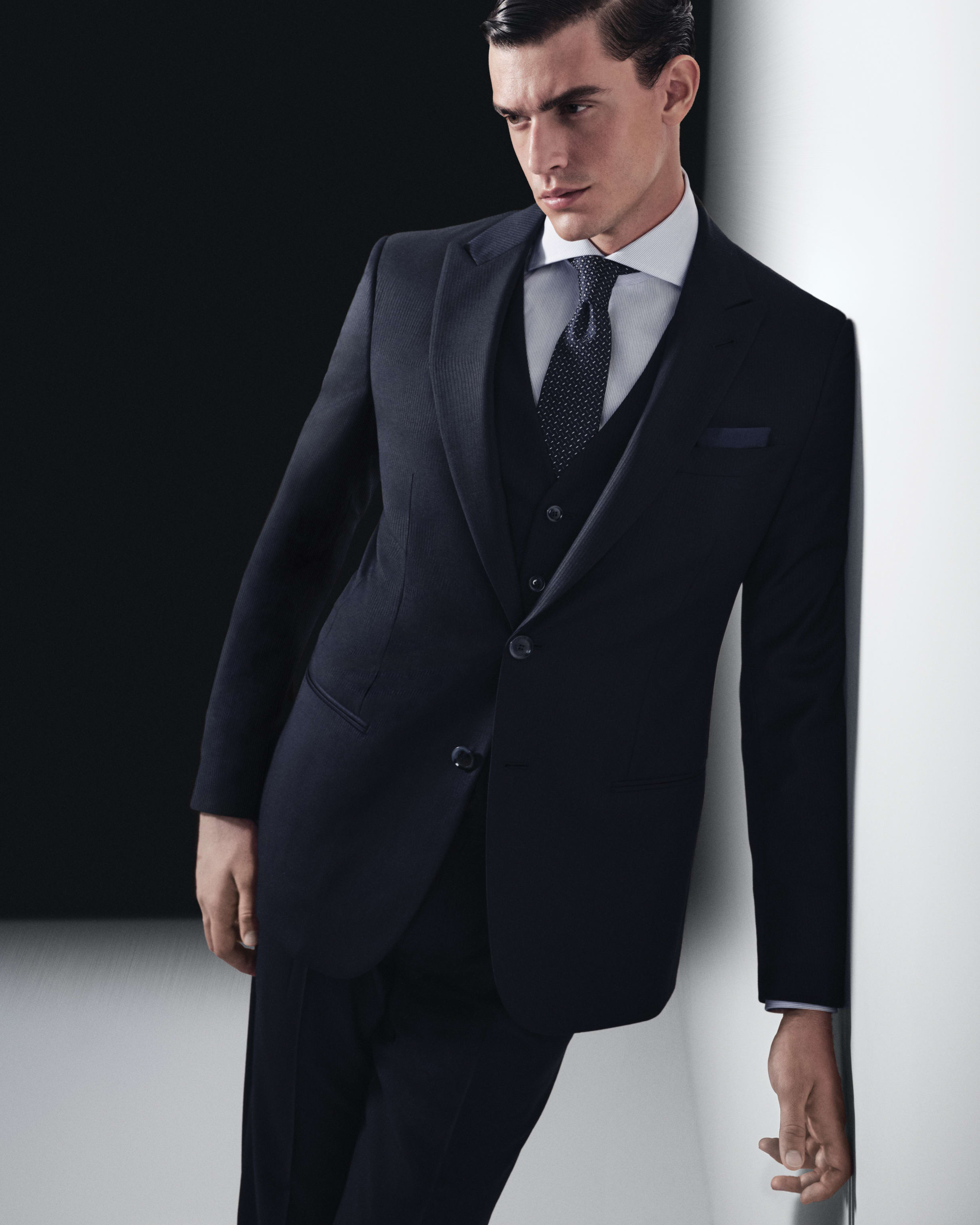 Model wearing a navy Giorgio Armani three-piece suit.