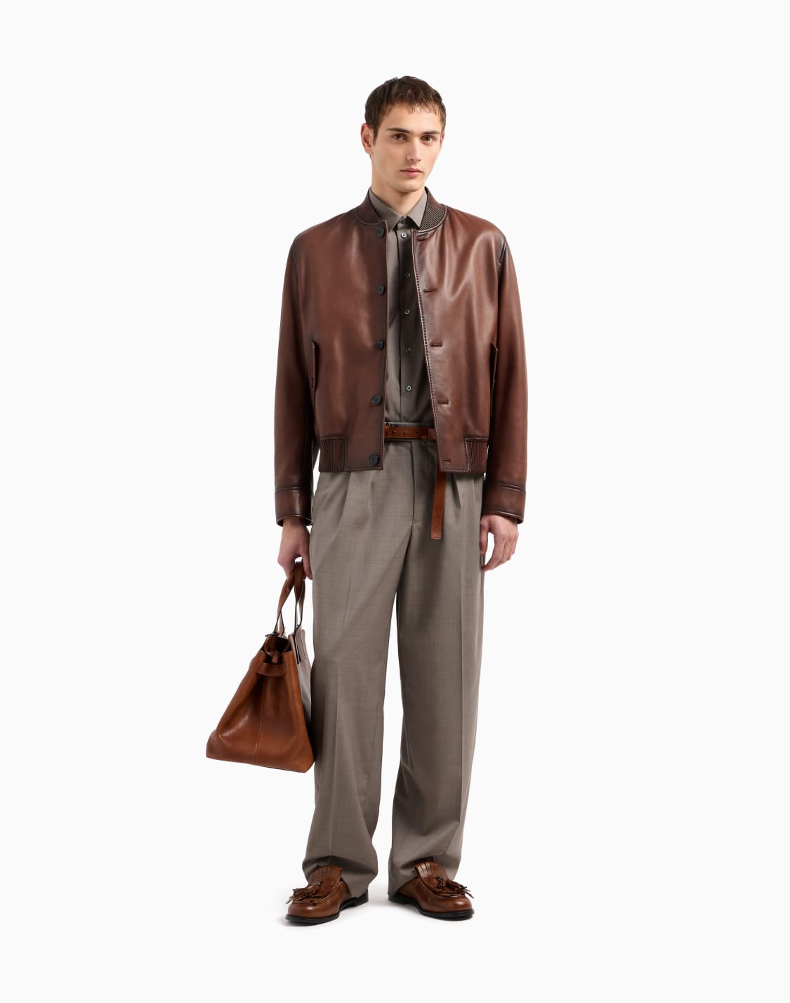Full-body outfit with a brown leather bomber, gray shirt, wide gray trousers, brown loafers and brown leather tote